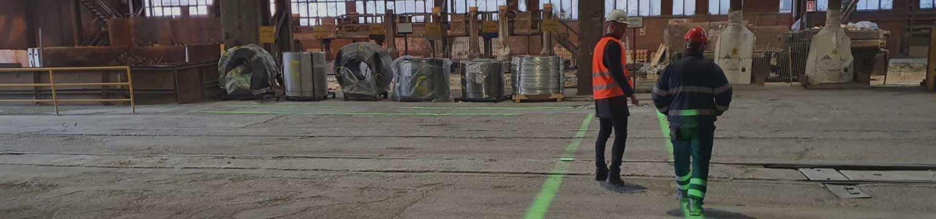 Two warehouse workers in protective gear standing by a safety projector line for laser walkways.